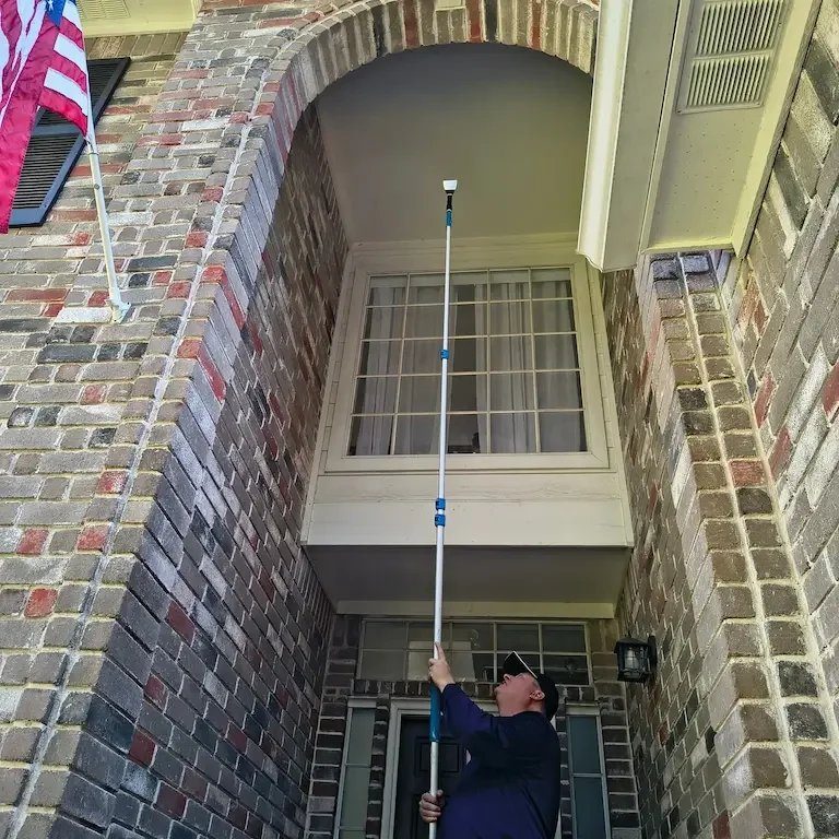 Sean of Texas Shield Pest Control treating the front door of a Fort Bend home, American flag on the porch